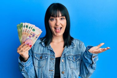 Arjantin pesolarını elinde tutan genç İspanyol kadın başarıyı mutlu bir gülümsemeyle kutluyor ve kazanan el kaldırarak ifade ediyor. 