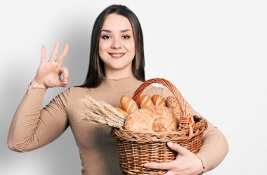 Hasır sepeti elinde tutan genç İspanyol kadın parmaklarıyla imza atıyor, gülümseyerek mükemmel bir sembol oluşturuyor. 