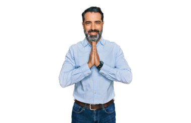 Orta yaşlı, sakallı, iş gömleği giyen, elleriyle dua eden, af dileyen, kendinden emin, gülümseyen bir adam.. 