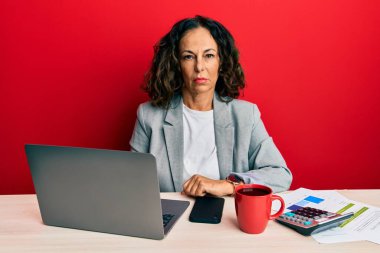 Ofiste çalışan orta yaşlı güzel bir kadın şüpheci ve gergin bir fincan kahve içiyor, sorun yüzünden surat asıyor. negatif kişi. 