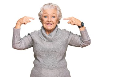 Kış süveteri giyen yaşlı, gri saçlı kadın iki eliyle başını gösteren gülümseme, harika bir fikir ya da düşünce, iyi bir hafıza 