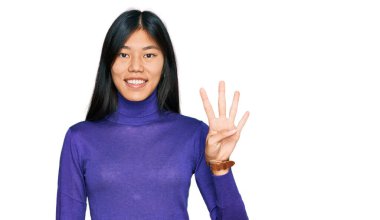 Güzel, genç Asyalı kadın gündelik giysiler giyer ve parmaklarını dört numarayı göstererek gülümserken kendinden emin ve mutluydu.. 