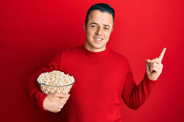 Handsome Young Man Eating Popcorn Smiling Happy Pointing Hand Finger — ストック写真