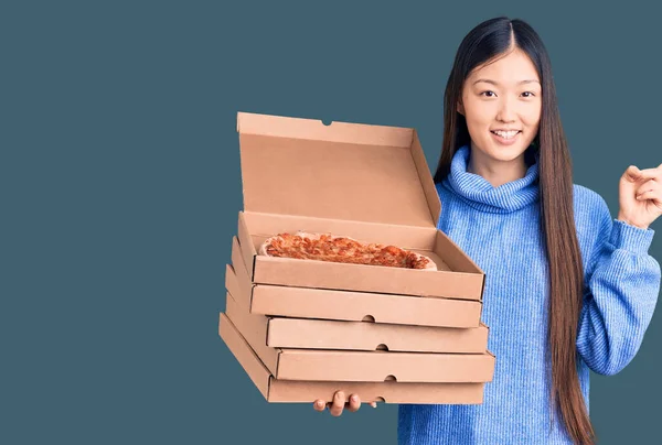 若いです美しい中国人女性保持段ボール箱のイタリアのピザ笑顔幸せなポインティングで手と指で側面 — ストック写真