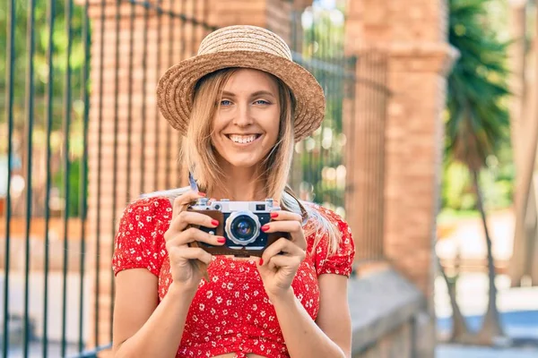 在城市里 年轻的金发女游客穿着夏装 用老式相机拍摄 — 图库照片