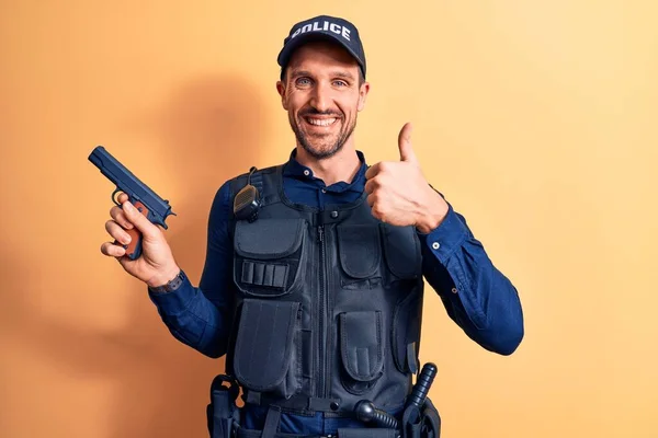Handsome Policeman Wearing Uniform Bulletprof Holding Gun Yellow Background Smiling — Stockfoto