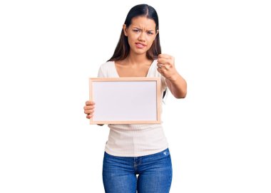 Elinde boş beyaz karatahta tutan genç ve güzel bir Latin kız öfkeyle bağırıyor, öfkeyle bağırıyor ve el kaldırıyor. 