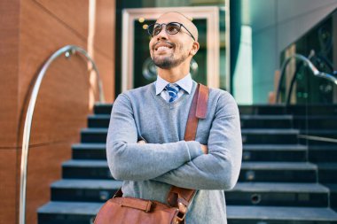 Genç Afrikalı Amerikalı iş adamı gülümseyerek şehirde mutlu bir şekilde yürüyor..