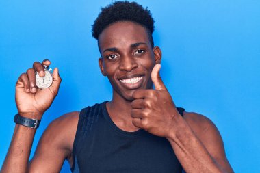Kronometre tutan genç Afro-Amerikan adam mutlu ve olumlu gülümsüyor, başparmağıyla mükemmel ve onay işareti yapıyor. 