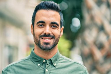 Genç İspanyol adam gülümseyerek şehirde mutlu mesut dikiliyor..