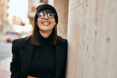 Genç İspanyol kadın gülümseyerek şehirde mutlu mesut dikiliyor..