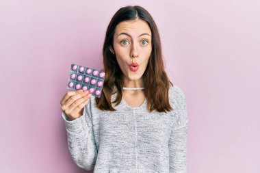 Genç esmer kadın elinde haplar tutuyordu. Korkmuş ve ağzı açık bir şekilde hayrete düşmüştü. 