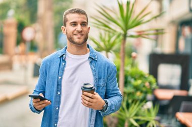 Kafkasyalı genç adam akıllı telefon kullanıyor. Şehirde kahve içiyor..