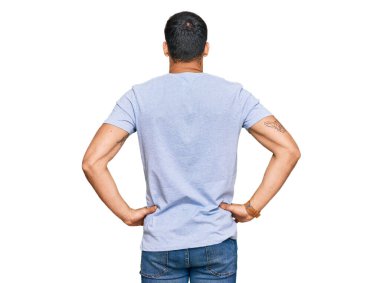 Gündelik kıyafetler giyen genç İspanyol adam kolları vücudunda geriye doğru bakıyor. 