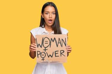 Güzel İspanyol kadının elinde güç pankartı var. Korkmuş ve şaşkına dönmüş ağzı açık, şaşırmış, inançsız bir yüz. 