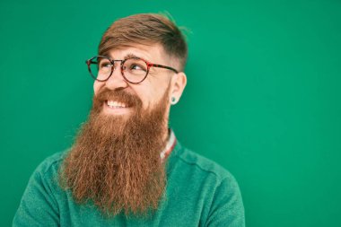 Kızıl saçlı genç İrlandalı adam gülümsüyor. Şehrin duvarına yaslanmış mutlu bir şekilde..