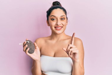 Elinde sünger taşıyla gülümseyen güzel bir orta doğulu kadın bir fikir ya da soruyla mutlu bir yüzle işaret ediyor. 