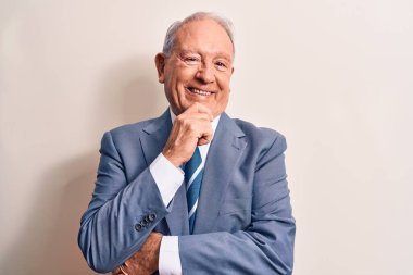 Beyaz arka planda zarif bir takım elbise giyen yakışıklı işadamı kameraya kollarını çapraz yapıp çenesine dokunarak gülümsüyor. Olumlu düşünüyorum..