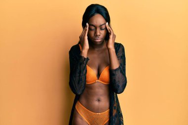 Genç Afro-Amerikan kadın stresten dolayı başı ağrıyan iç çamaşırı giyiyor. migren ağrısı. 