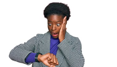 Gündelik giysiler giymiş genç Afrikalı Amerikalı kız saate bakıyor endişeli, geç kalmaktan korkuyor. 