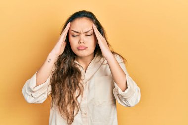 Elleri başının üstünde, günlük kıyafetler giyen genç İspanyol kız, stresten baş ağrısı çekiyor. migren ağrısı. 