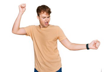 Kafkasyalı genç adam gündelik kıyafetler giymiş mutlu ve neşeli dans ediyor, gülümsüyor rahat ve kendinden emin bir şekilde müzik dinliyor. 