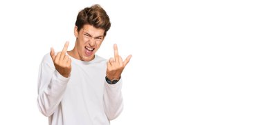 Handsome caucasian man wearing casual white sweater showing middle finger doing fuck you bad expression, provocation and rude attitude. screaming excited 
