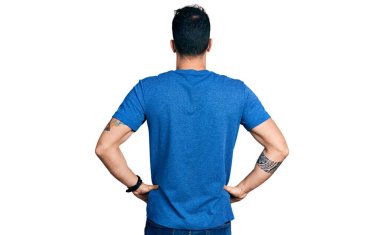 Gündelik tişört giyen genç İspanyol adam kolları vücudunda geriye doğru bakıyor. 