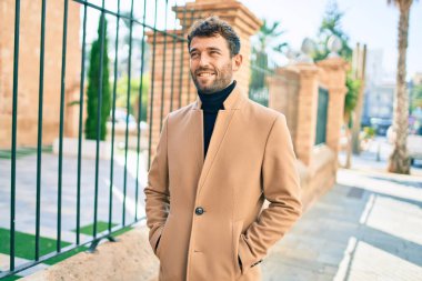 Zarif ceket giyen yakışıklı iş adamı dışarıda mutlu bir şekilde gülümsüyor.