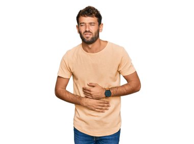 Sakallı, eli karnında rahat bir tişört giyen yakışıklı genç bir adam. Çünkü hazımsızlık, acı verici bir hastalık ve kendini iyi hissetmiyor. Ağrı kavramı. 