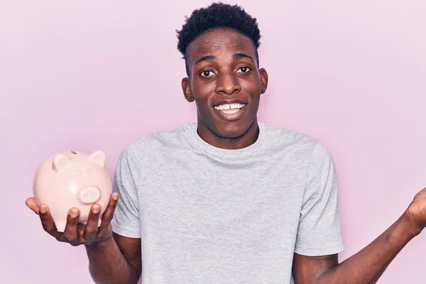 Jovem Afro Americano Segurando Porquinho Banco Celebrando Realização Com Sorriso — Fotografia de Stock