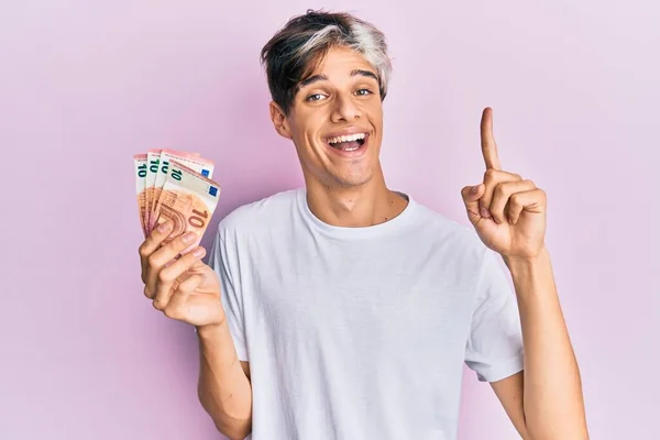 Joven Hispano Sosteniendo Montón Billetes Euros Sonriendo Con Una Idea —  Fotos de Stock