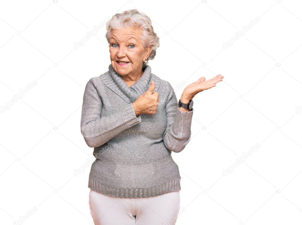 Senior grey-haired woman wearing casual winter sweater showing palm hand and doing ok gesture with thumbs up, smiling happy and cheerful 