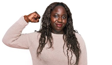 Genç Afrikalı kadın yün kazak giyiyor güçlü kol kası gösteren, kendinden emin ve gururlu biri. 