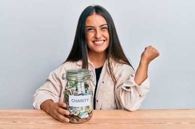 Güzel İspanyol kadın elinde para dolu kavanozla gururla haykırıyor zaferi kutluyor ve başarıyı kollarını kaldırarak kutluyor. 