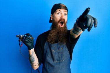 Uzun sakallı, profesyonel üniformalı, eldivenli, uzun sakallı bir adam. Parmakları önde, ağzı açık, şaşırmış, ön tarafta bir şey var. 