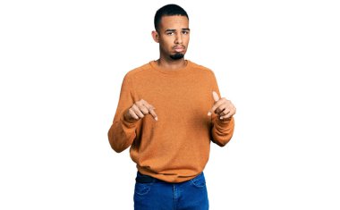 Genç Afro-Amerikan adam günlük giysiler giymiş üzgün ve üzgün görünüyor, parmaklarıyla yön gösteriyor, mutsuz ve depresif.. 