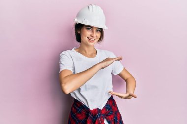 Beyaz şapkalı genç bir kadın. Elleriyle büyük ve büyük bir işaret gösteriyor. Ölçü sembolü. Kameraya bakıp gülümsüyor. ölçüm kavramı. 