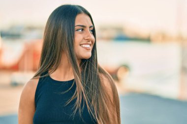 Genç İspanyol kız gülümseyerek şehirde mutlu mesut dikiliyor..