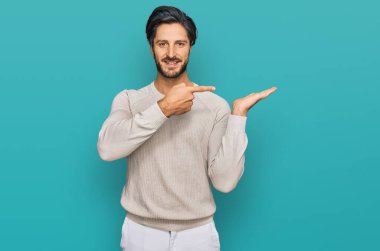 Gündelik kıyafetler giyen genç İspanyol adam kameraya hayret ediyor ve gülümsüyor.. 