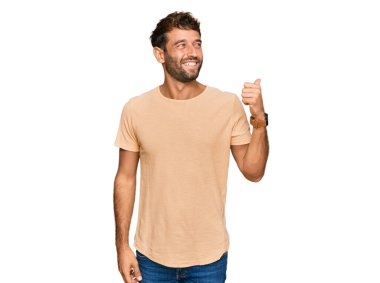 Sakallı, sıradan tişörtlü, neşeli yüzlü, gülümseyen ve baş parmağıyla yüzünü gösteren yakışıklı bir genç.. 