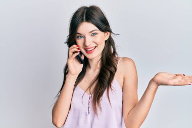 Young beautiful caucasian girl having conversation talking on the smartphone celebrating achievement with happy smile and winner expression with raised hand 