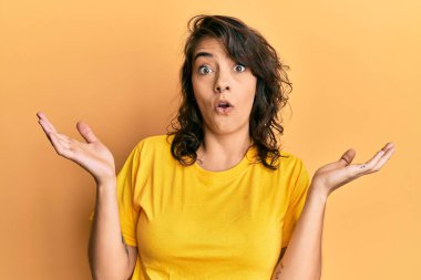 Sıradan sarı tişört giyen genç İspanyol kadın hiçbir şey bilmiyor ve kolları açık, hiçbir fikrim yok ve şüpheli bir yüz var.. 
