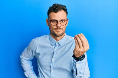 Gündelik kıyafetler ve gözlük takan genç İspanyol adam İtalyan jesti yapıyor. Elleri ve parmakları kendinden emin. 