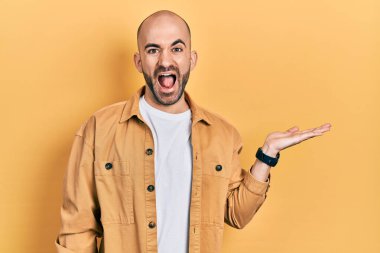 Genç kel adam avuçlarını açmış, elinde çılgınca bir şey tutuyor ve başarı için hayretle haykırıyor, heyecanla haykırıyor. 