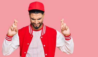 Beyzbol üniforması giyen sakallı genç adam umut ve gözlerin kapalı gülümseyerek el sallıyor. Şans ve batıl inançlar. 