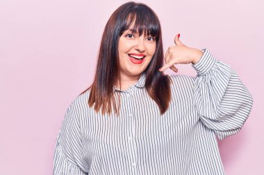 Genç ve cüsseli bir kadın günlük kıyafetler giyiyor gülümsüyor telefonla el ve parmaklarıyla jest yapıyor telefonda konuşuyor gibi. iletişim kavramları. 