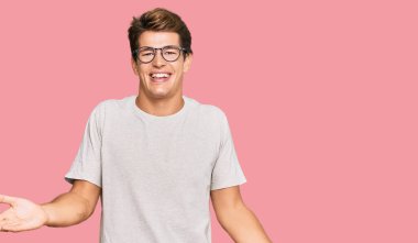 Handsome caucasian man wearing casual clothes and glasses smiling cheerful with open arms as friendly welcome, positive and confident greetings 