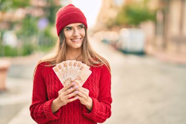 Şehirde elinde Türk lirası banknotları tutan yün şapkalı genç İspanyol kadın..