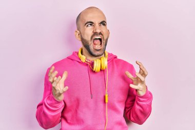 Spor kıyafetleri giymiş, kulaklık takmış deli gibi bağırıyor ve bağırıyor. Saldırgan bir ifade ve kollar havada. hüsran kavramı. 